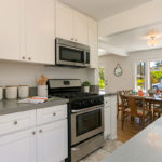 white kitchen cabinets and view of the dining room and large window with views of the street