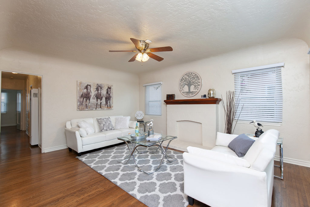 staged living room with white sofas and glass table and rug