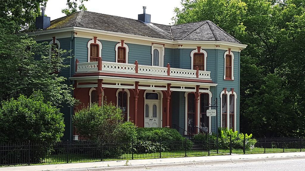 A Victorian-style two-story home with a blue and brown façade.