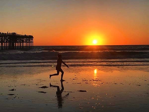 child running on a beach in San Diego during sunset