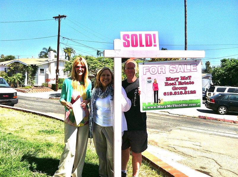 Realtor and clients standing by the sold sign