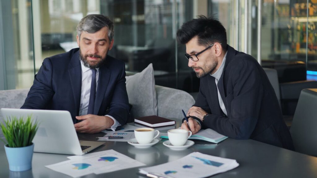 Businessmen Discussing with Laptop and Charts