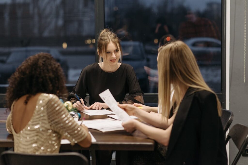 Three Women at a Table Discussing Some Paperworks