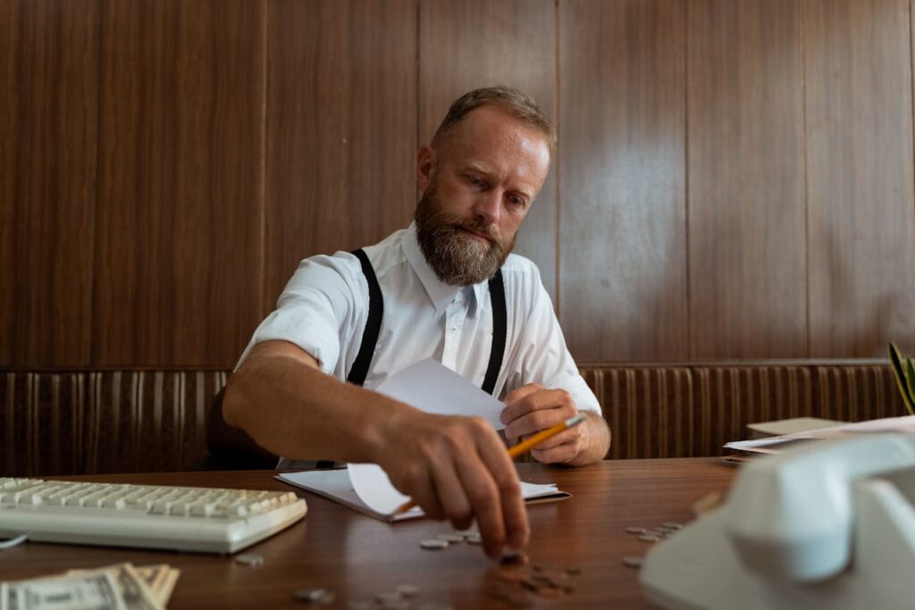 A Man Counting Coins in a Wooden Table