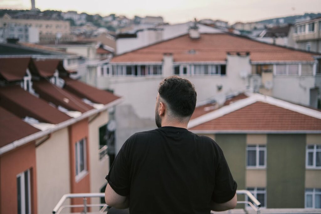 Man on Balcony Looking on Cityscape