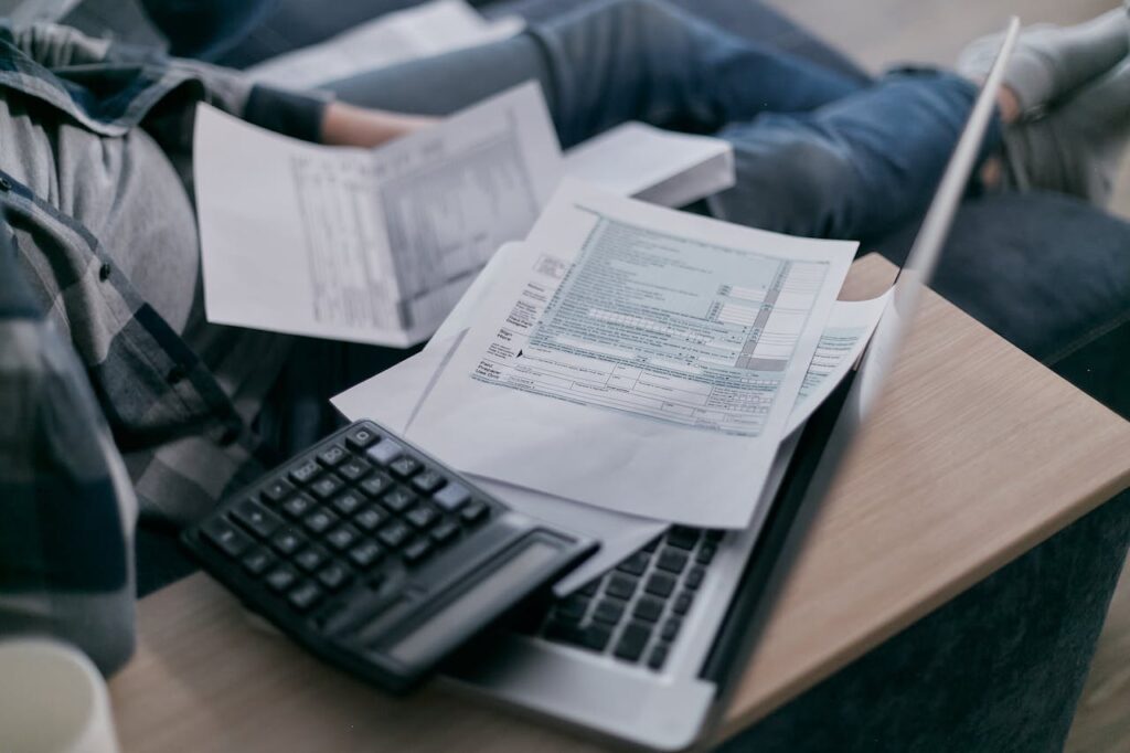 Some Printed Documents on Top of a Brown Table with a Calculator