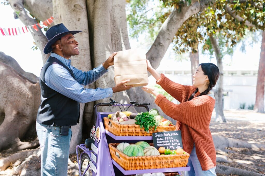 A Man Handing Over the Paper Bag to His Customer in Knitted Sweater