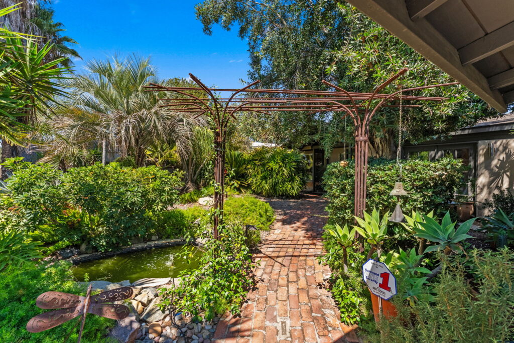 views of lush mature landscape in front of home and arbor