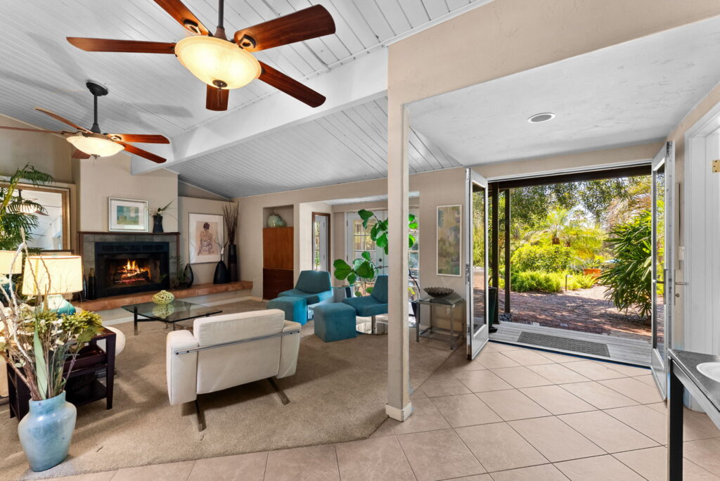 family room with light colore furniture, glass coffee table, fireplace and views of outside and columns in family room