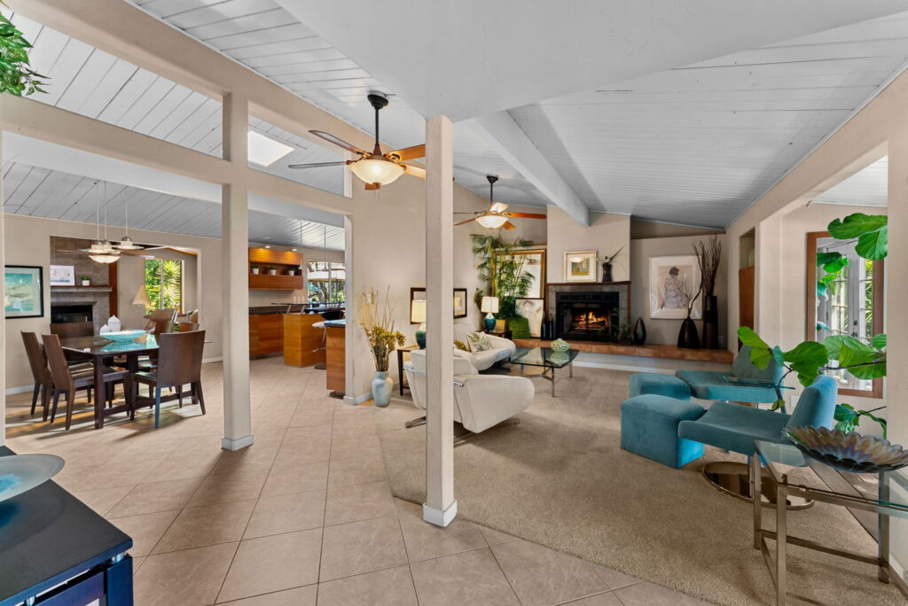 family room with light colore furniture, glass coffee table, fireplace and views of kitchen and columns in family room