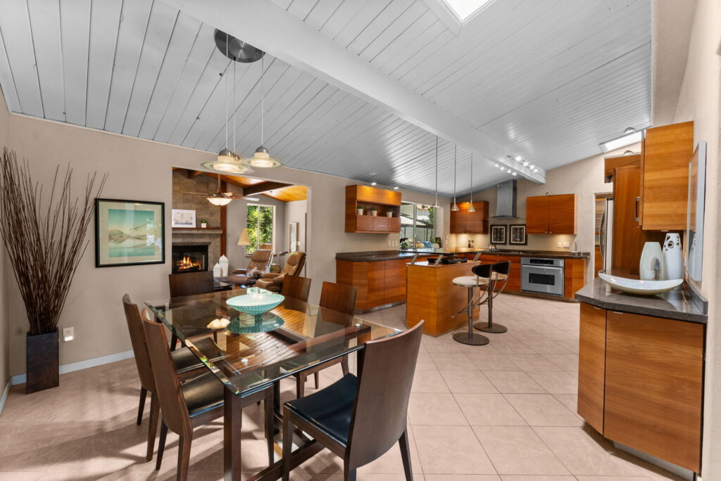 open style kitchen with maple colored kitchen cabinets, an aisle and stainless steel appliances and views of the living room