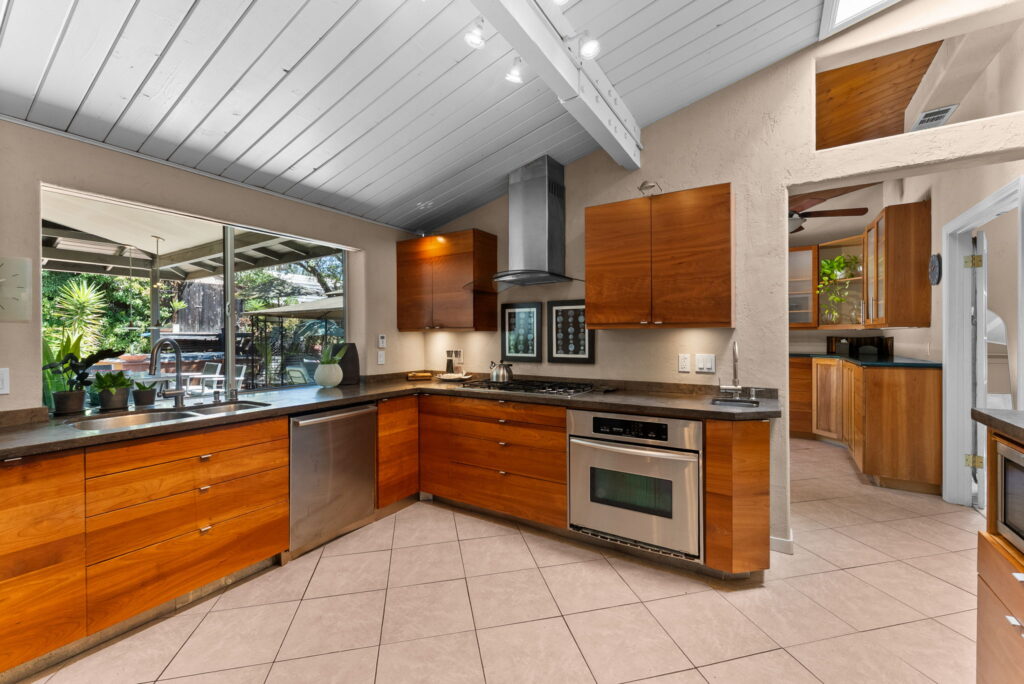 open style kitchen with maple colored kitchen cabinets, an aisle and stainless steel appliances