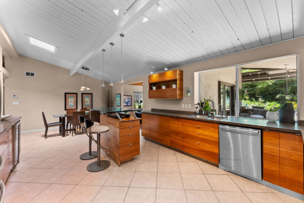 open style kitchen with maple colored kitchen cabinets, an aisle and stainless steel appliances