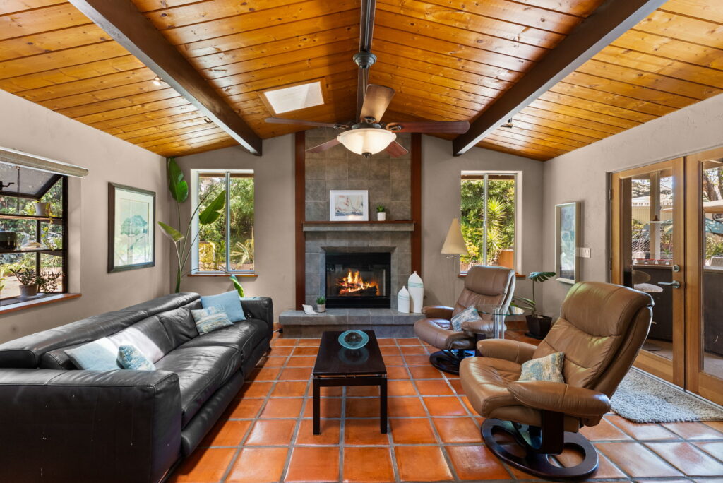 living room with brown sofa and furniture beamed ceiling, fireplace and french doors leading outside