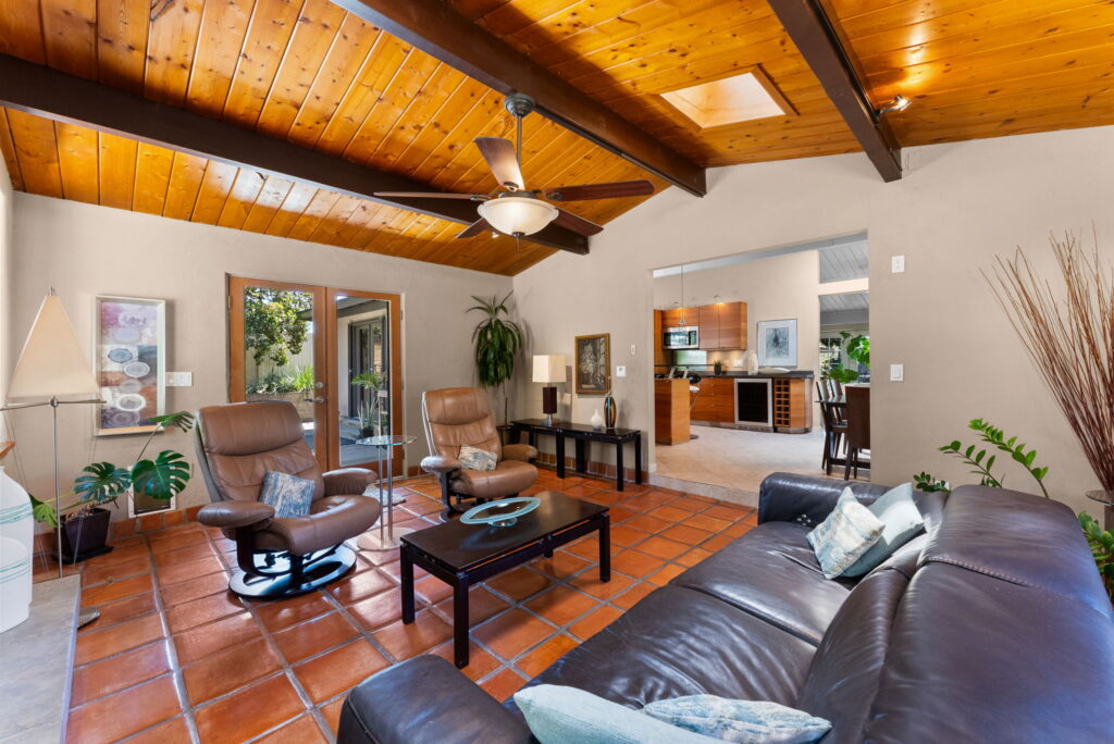living room with brown sofa and furniture beemed ceiling and french doors leading outside