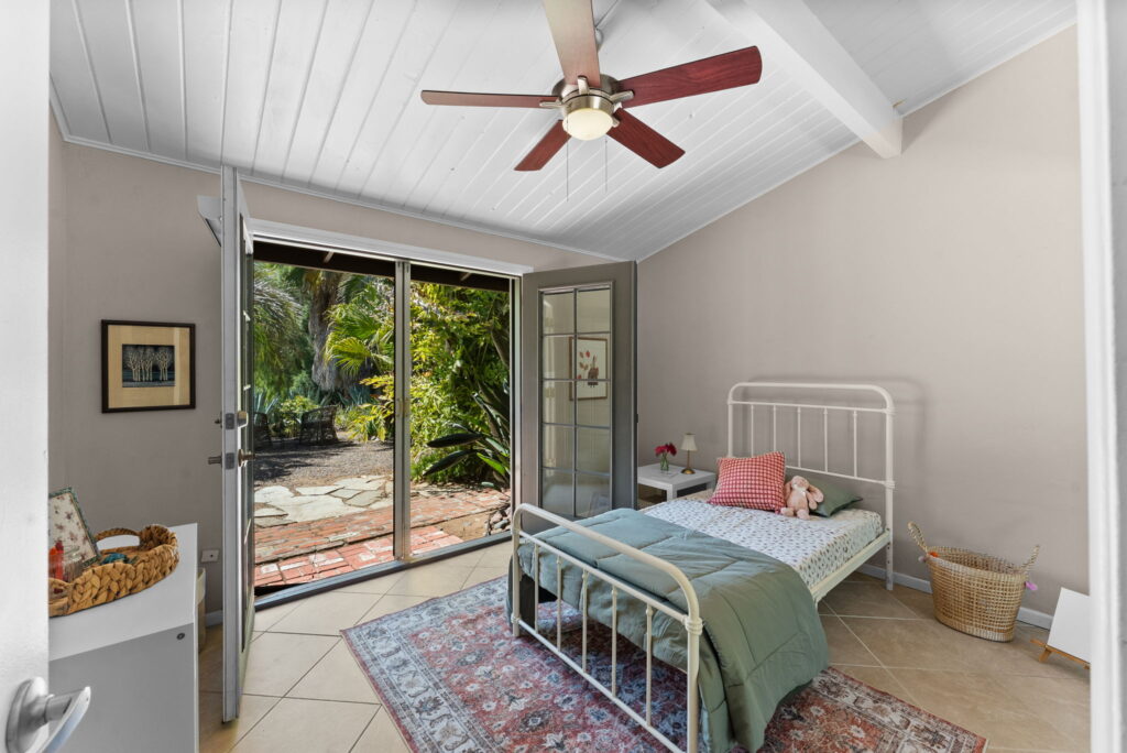 large bedroom with grey bedding, and open french doors to outside