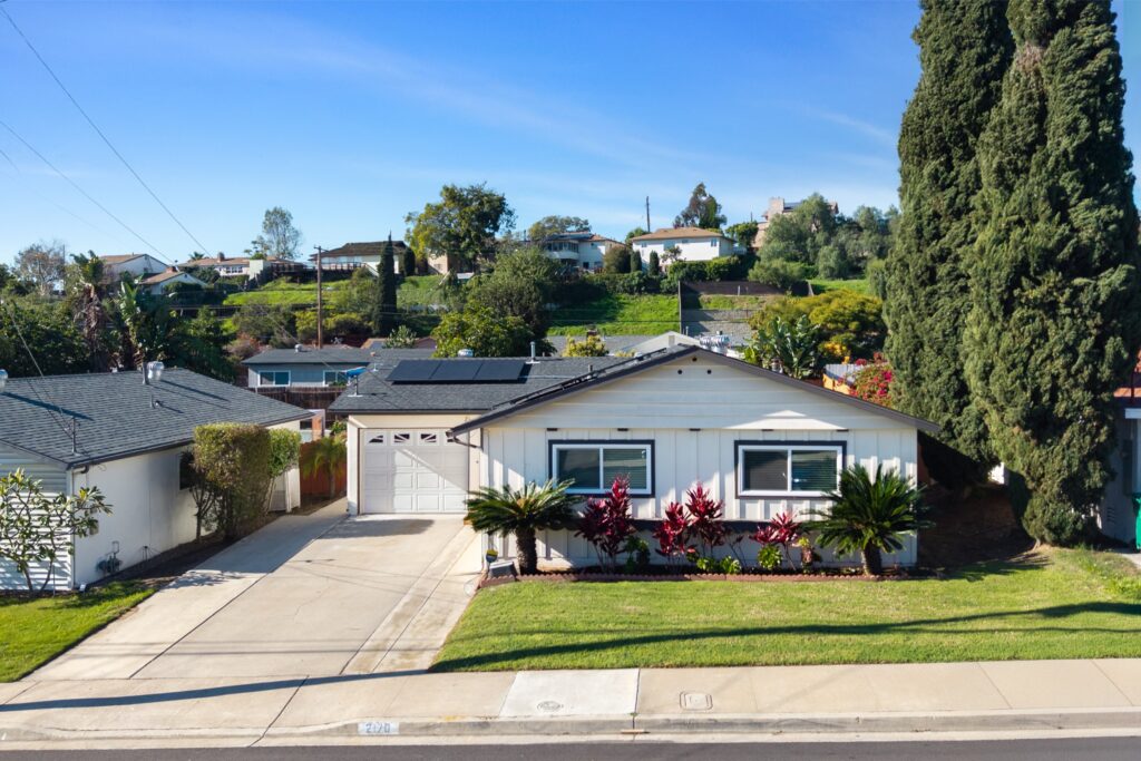Elevated wide-angle view of the residential home at 2170 Montclair St, North Park, highlighting the driveway, attached garage, and lush green lawn with palm trees.