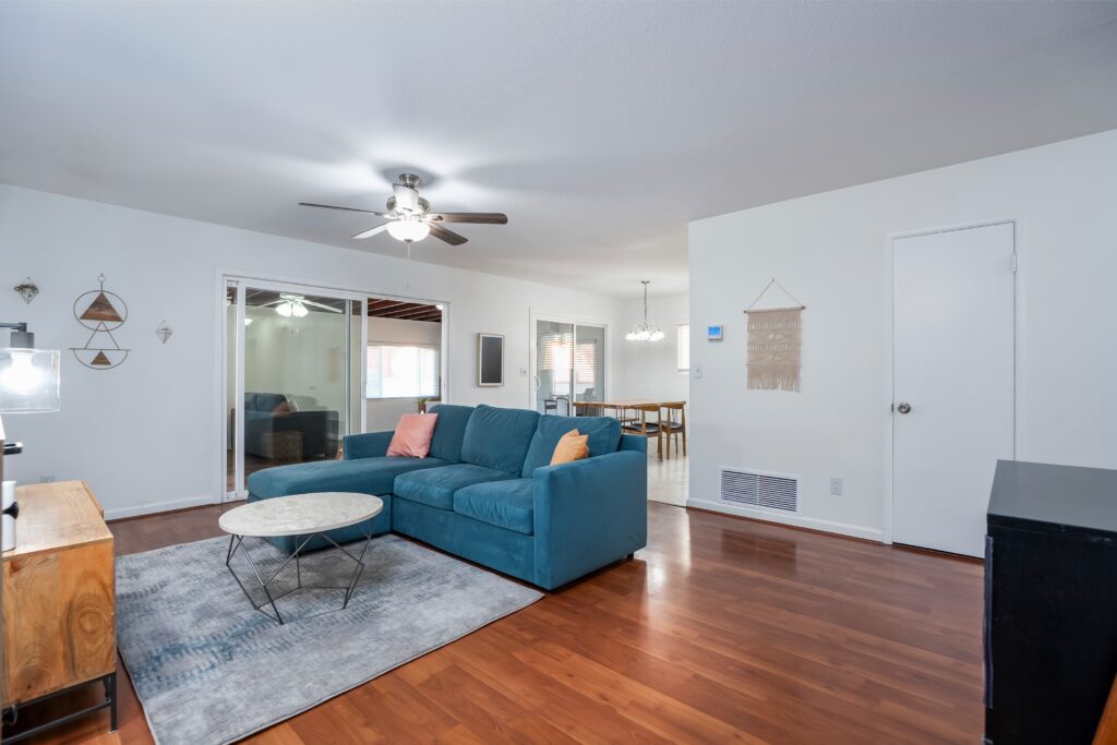 Interior view of 2170 Montclair St in North Park featuring a blue velvet sofa, modern coffee table, and sliding glass doors to the sunroom.