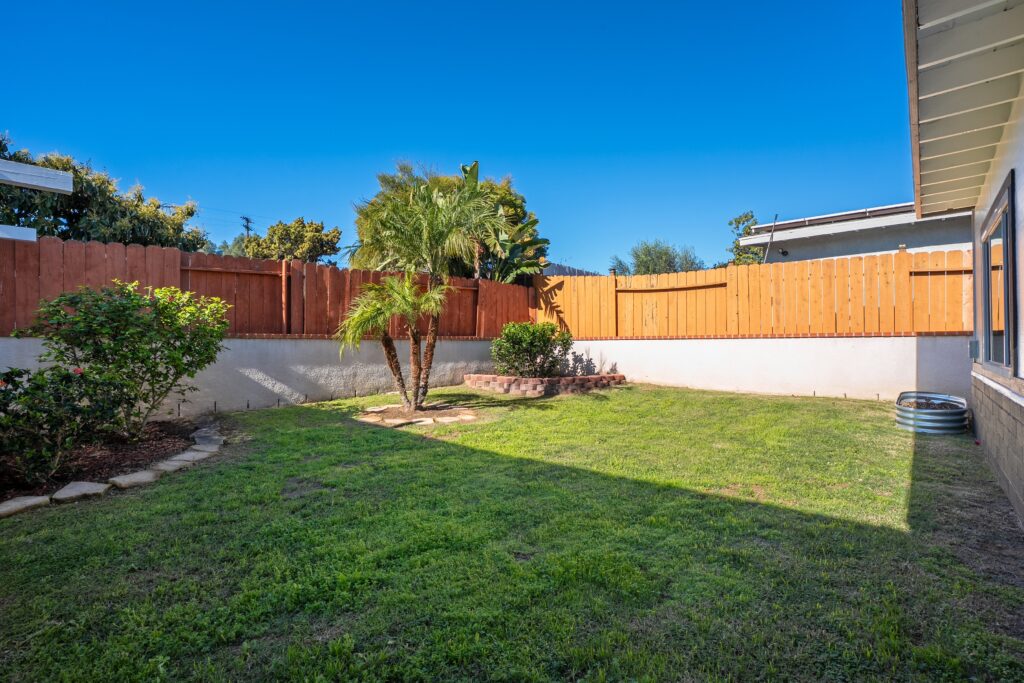 Private backyard with lush lawn and palm trees at 2170 Montclair St North Park, perfect for a creative home office or outdoor relaxation.